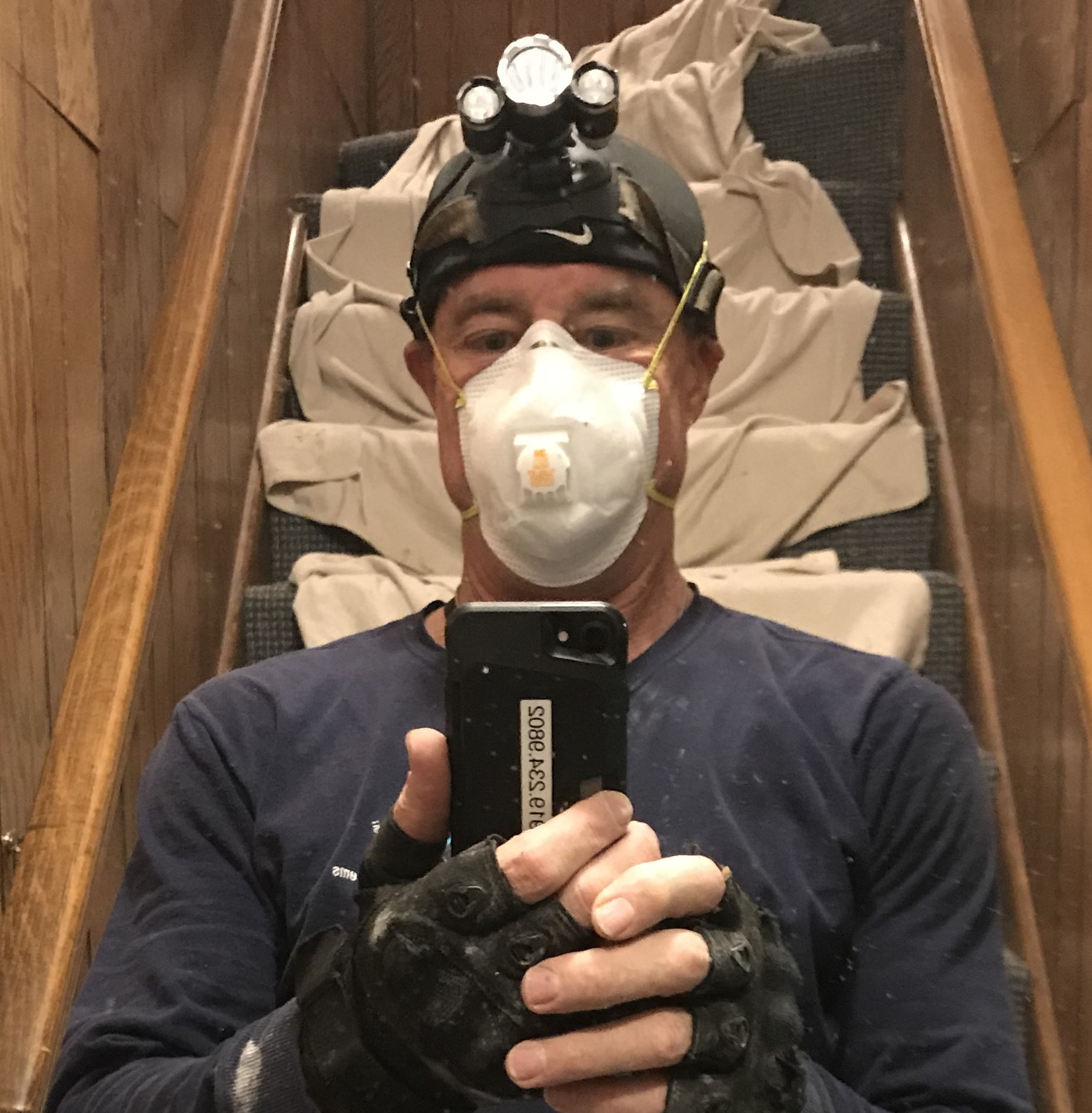 Steve McLeod inspecting a crawlspace with headlamp and respirator